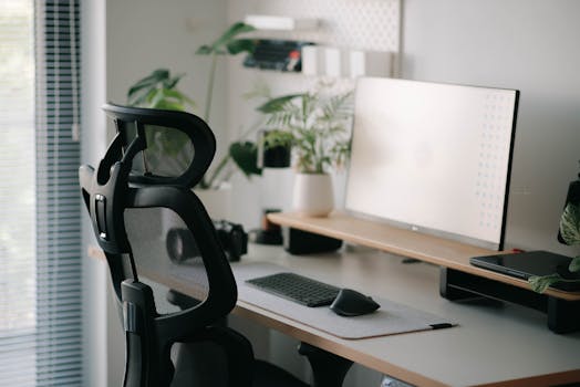 Stylish home office setup featuring an ergonomic chair, large monitor, and plants for a calming work environment.
