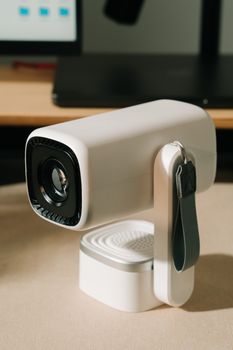 A sleek white portable projector with strap on a desk, perfect for home entertainment or business meetings.