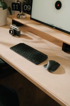A minimalist desk setup featuring a keyboard, mouse, and a vintage camera under soft lighting.