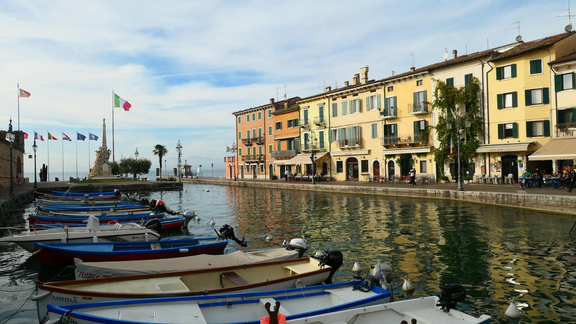 A vibrant view of Lazise marina with colorful buildings and boats on a sunny day.