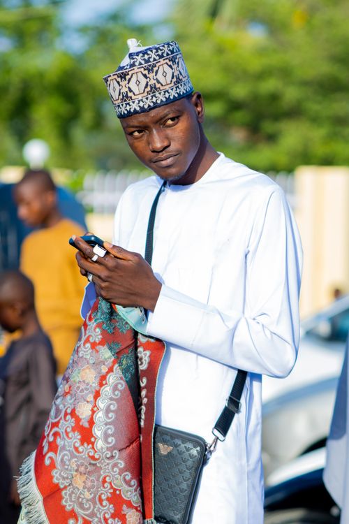 Free Young man in traditional attire, holding a colorful fabric, outdoors. Stock Photo