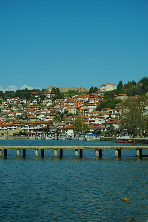 Free Beautiful lakeside view of Ohrid with North Macedonian flag and distant fortress. Stock Photo