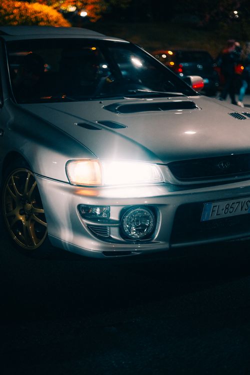 Free Close-up of a sleek car with headlights on, captured at night outdoors. Stock Photo