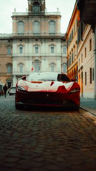 Elegant red sports car parked on a historical European street with classic architecture backdrop.