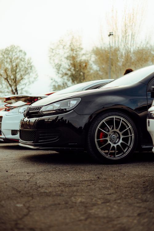 Free A sleek black car on display at an outdoor car show with a focus on the wheel. Stock Photo