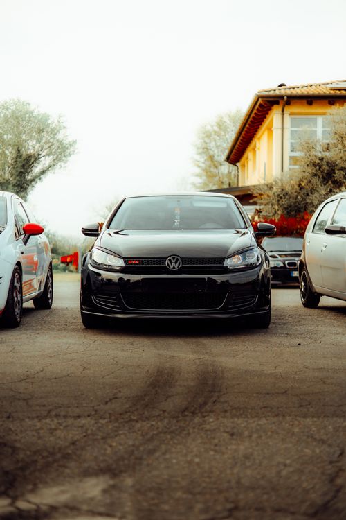 Free A sleek black car parked on a driveway between two other cars in a residential area outdoors. Stock Photo