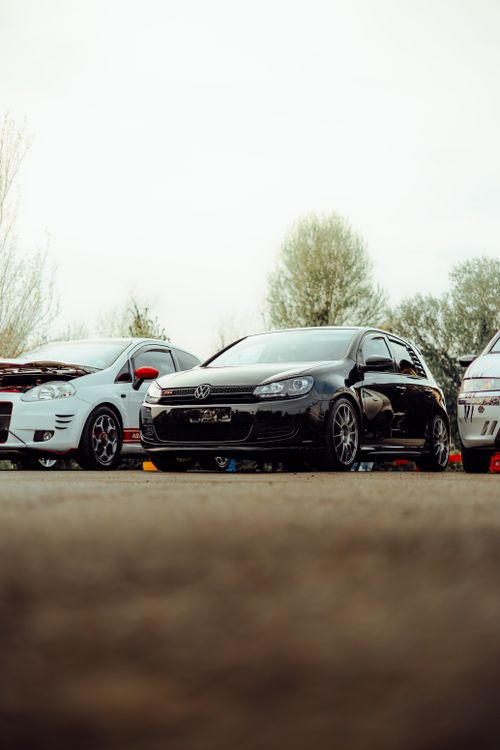 Free Black and white cars parked at an outdoor car exhibition with trees in the background. Stock Photo