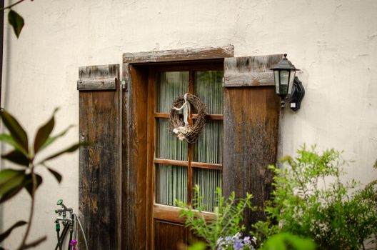 Charming wooden door with a decorative wreath and rustic lantern, surrounded by greenery.