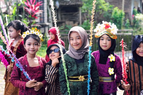 Free Group of children in colorful traditional Indonesian clothing with decorative headpieces and props. Stock Photo