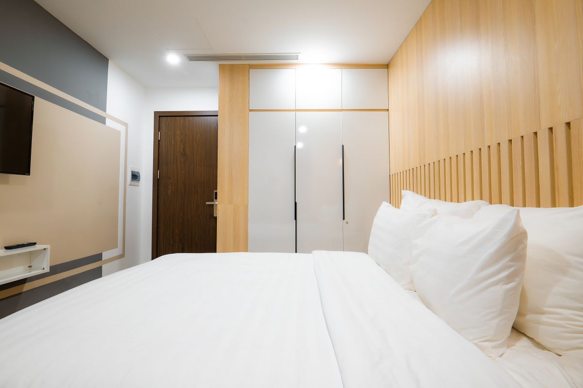 Minimalist modern hotel room interior with cozy bed and wooden panels