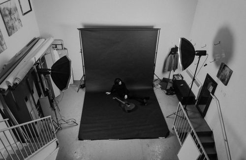 Free Aerial black and white photo of a studio setup with a subject posing with a guitar. Stock Photo