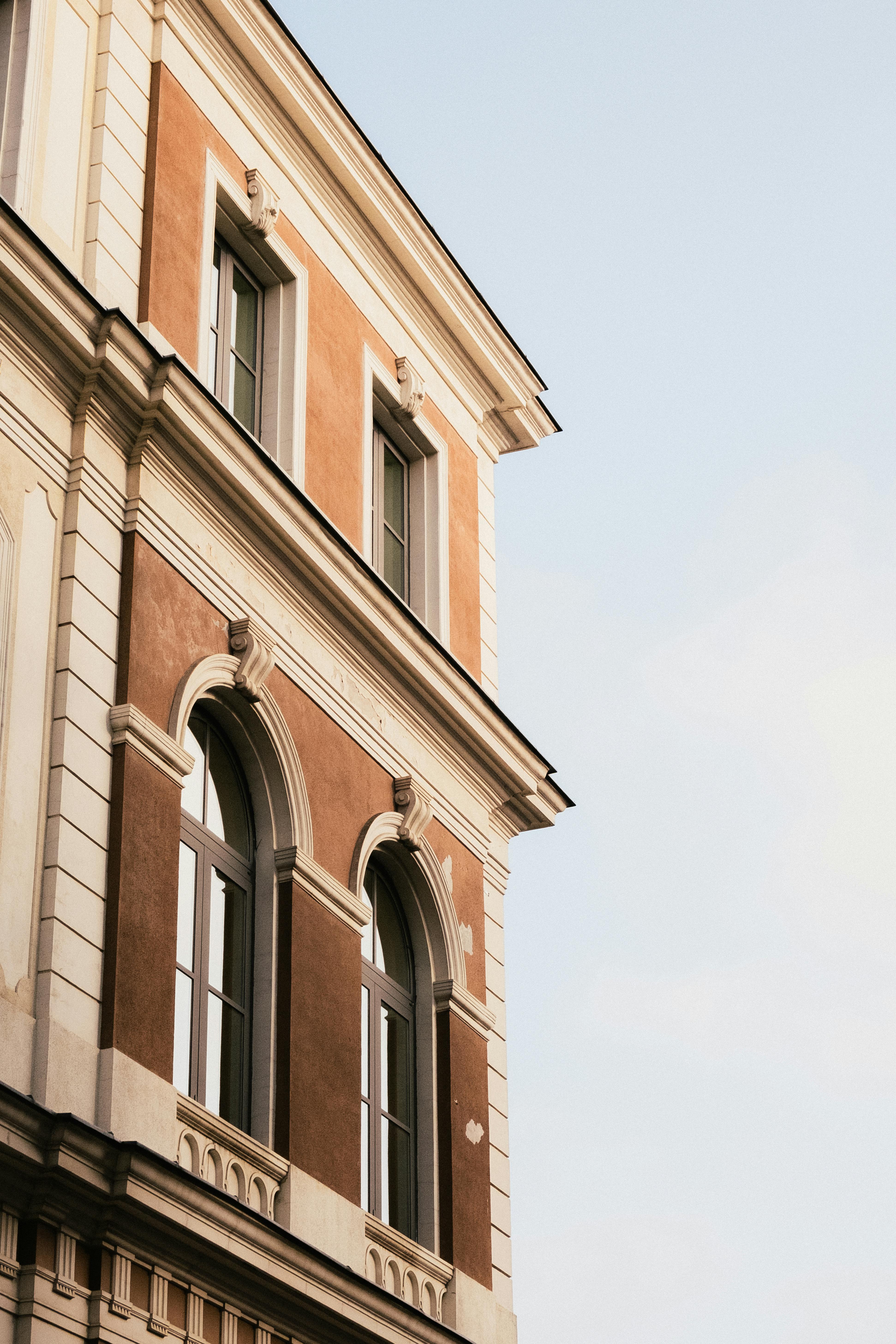 A classic European building with arched windows and ornate details against a soft blue sky, capturing elegance and historic charm.
