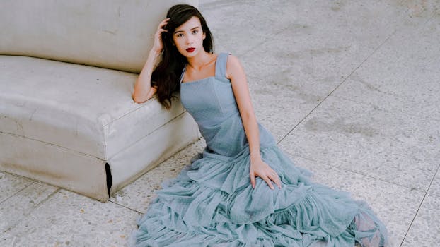 一位时尚女士穿着别致的蓝色连衣裙，在室内的沙发上优雅地摆出姿势