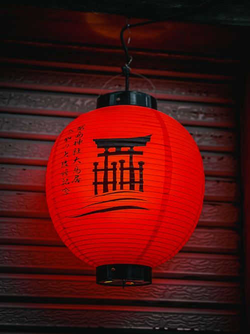 Free Red paper lantern with Torii gate symbol, iconic in Japanese culture, hanging against wooden backdrop. Stock Photo