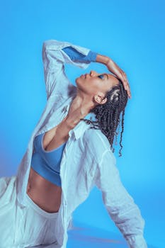 Graceful woman posing elegantly with an artistic flair against a vibrant blue backdrop.