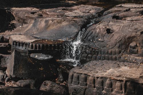 Free Detailed ancient stone carvings at Kbal Spean waterfall in Cambodia's serene outdoors. Stock Photo