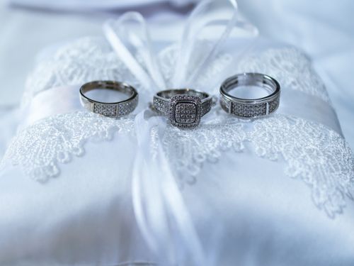 Free Three silver wedding rings displayed on a lace-decorated pillow, symbolizing love and commitment. Stock Photo