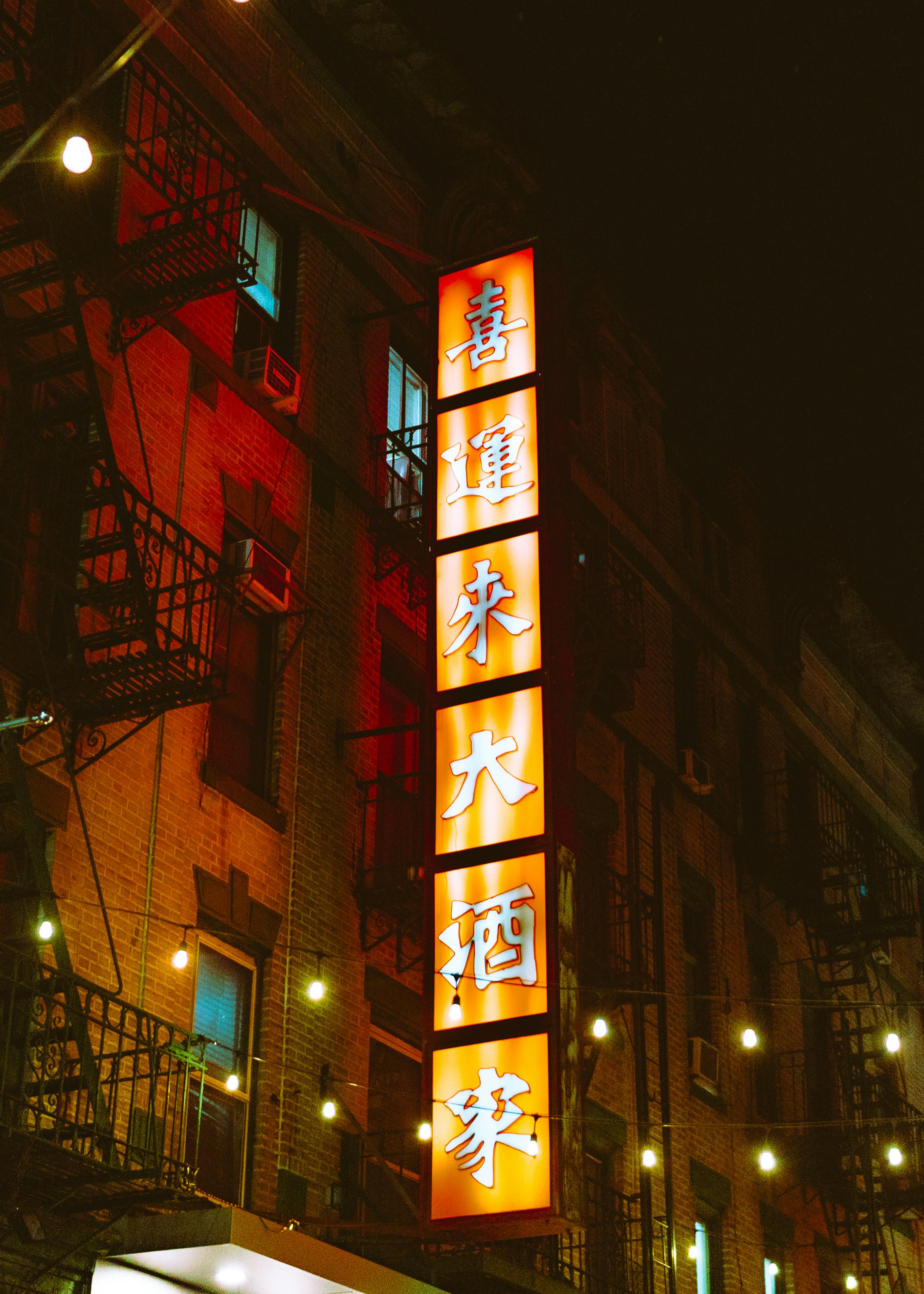 Ücretsiz Canlı neon tabela, gece vakti New York'un Manhattan semtindeki Chinatown'da bir binanın cephesini aydınlatıyor. Stok Fotoğraflar