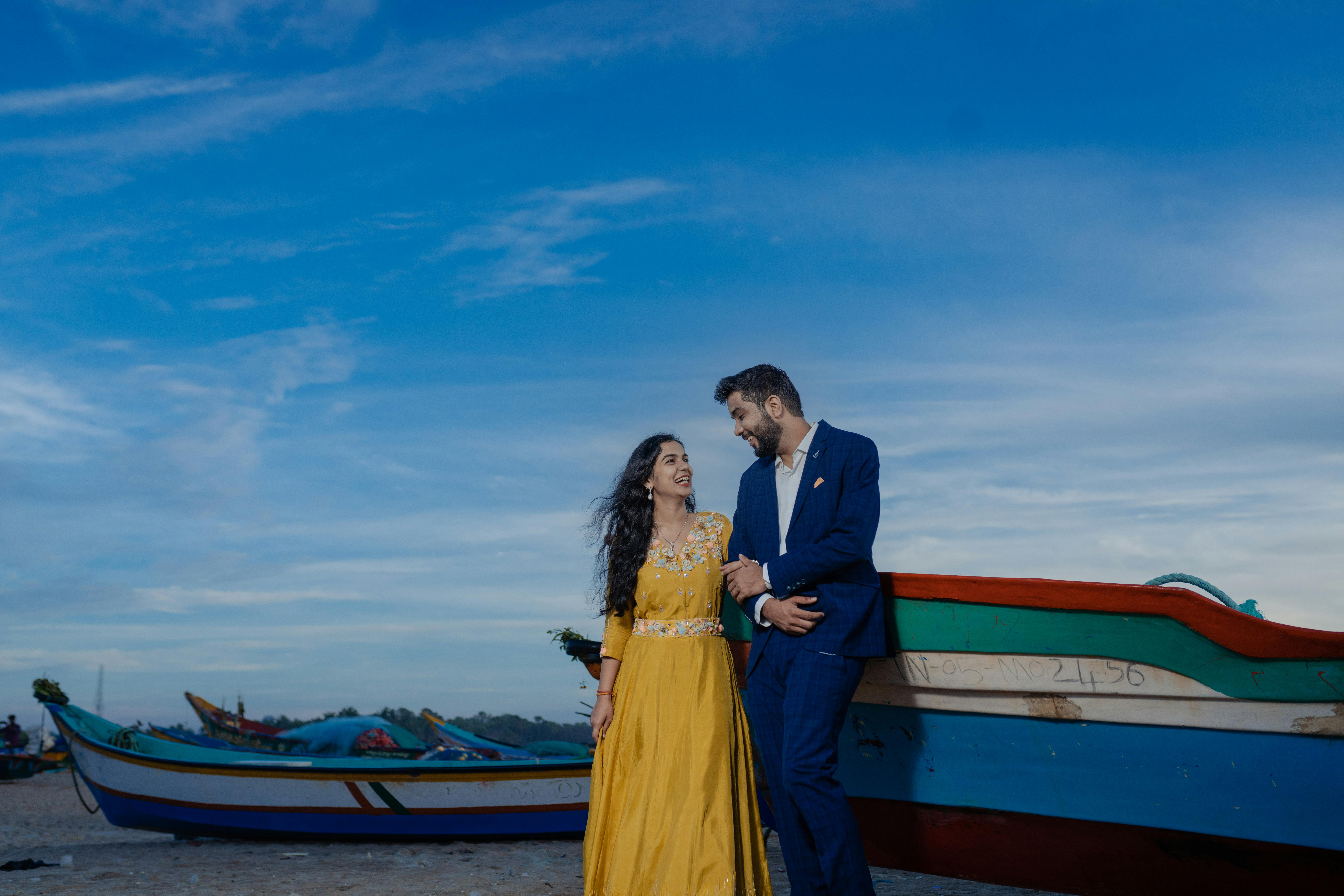 A couple enjoying a romantic moment near colorful boats at the beach during the day.