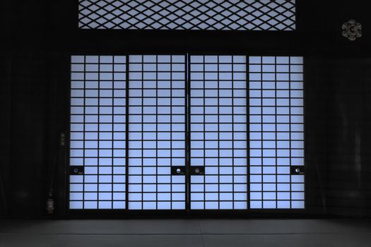 Elegant view of a traditional Japanese shoji door with soft lighting, creating a serene indoor atmosphere.