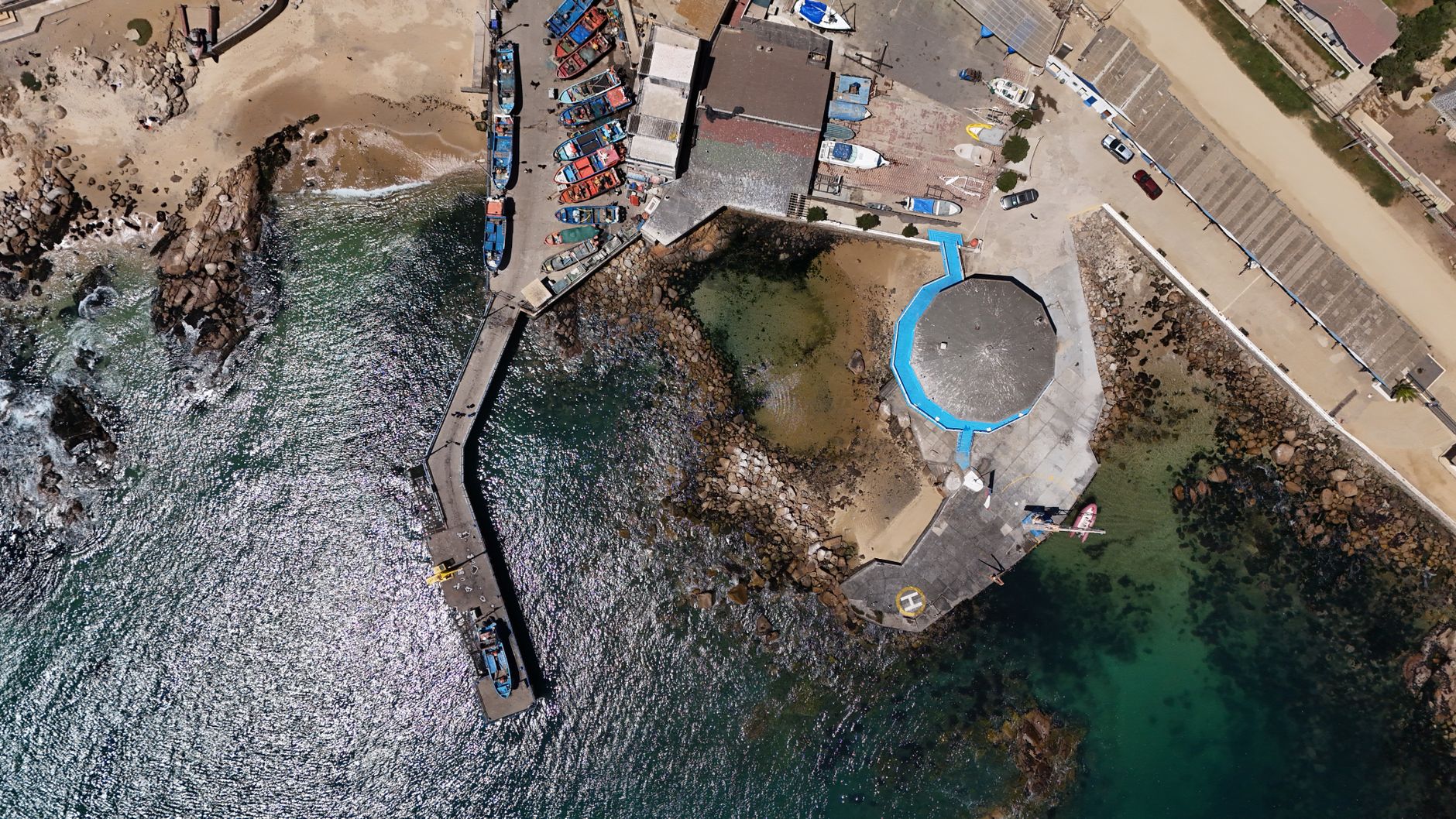 An aerial perspective of a bustling dock with vibrant boats in El Quisco, Chile.