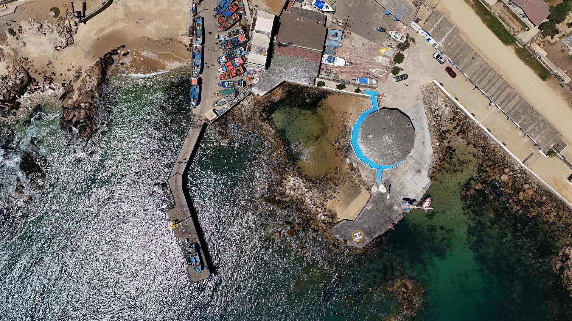 An aerial perspective of a bustling dock with vibrant boats in El Quisco, Chile.