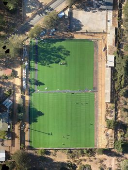 Top-down view of a verdant soccer field surrounded by trees and facilities, ideal for sports concepts.