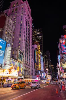 Bustling Times Square at night with colorful billboards and taxis, capturing NYC's iconic energy.