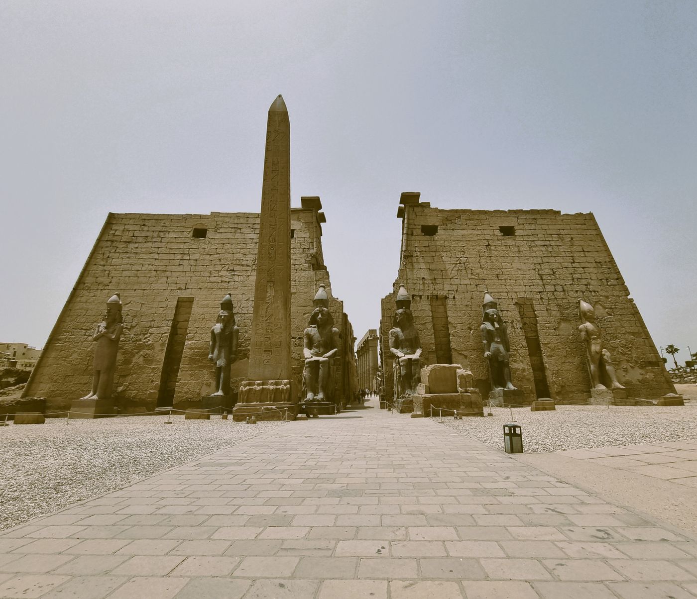 The entrance pylon of Luxor Temple with its obelisk and seated statues of Ramesses II under a clear sky