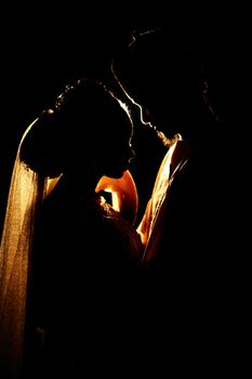 A beautiful silhouette of a bride and groom sharing a tender moment, captured with dramatic lighting.