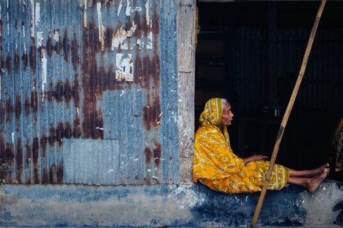 Free Elderly woman sitting in a doorway in Chilmari, Bangladesh, showcasing cultural heritage. Stock Photo