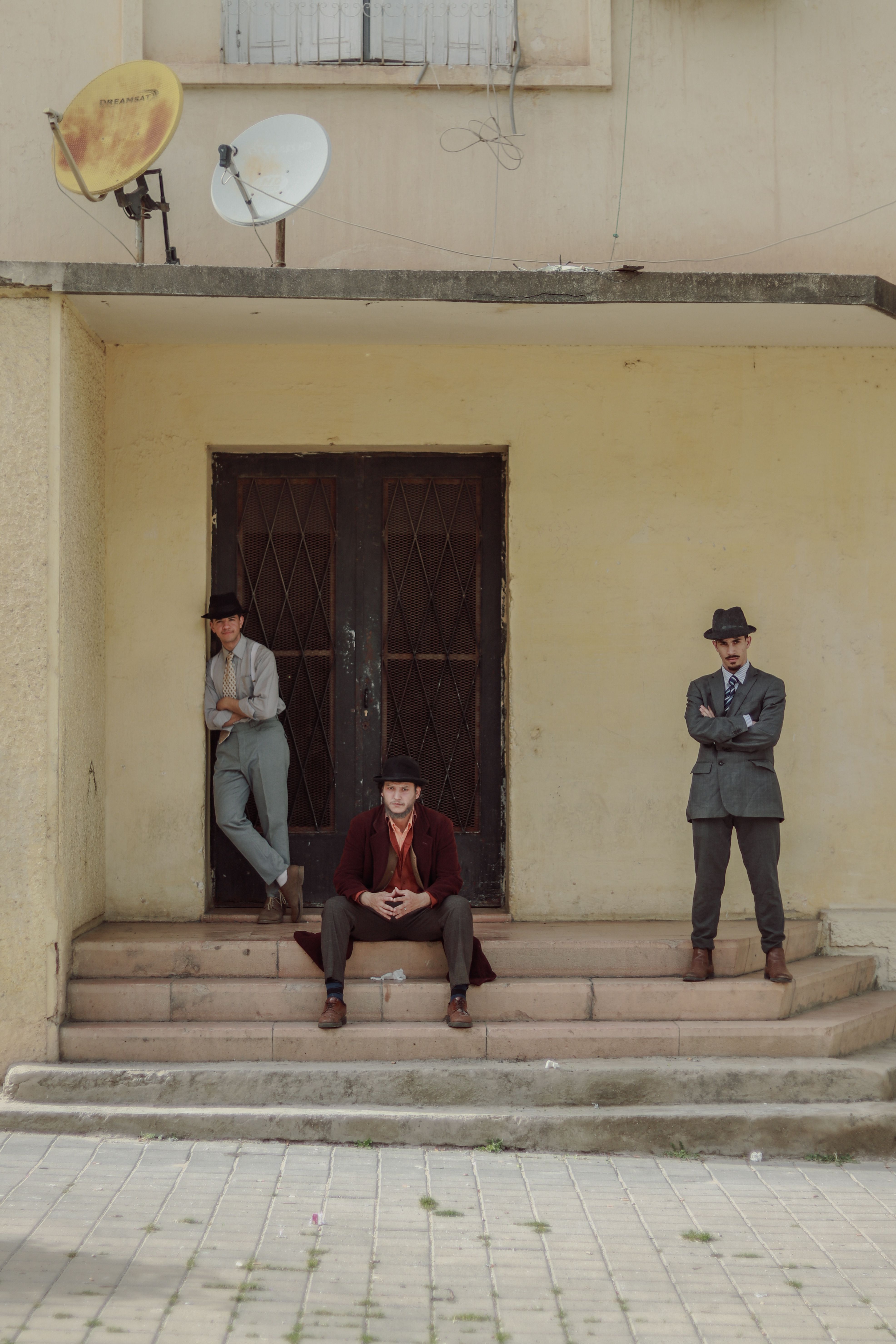 Three Men in Vintage Suits on Building Steps · Free Stock Photo