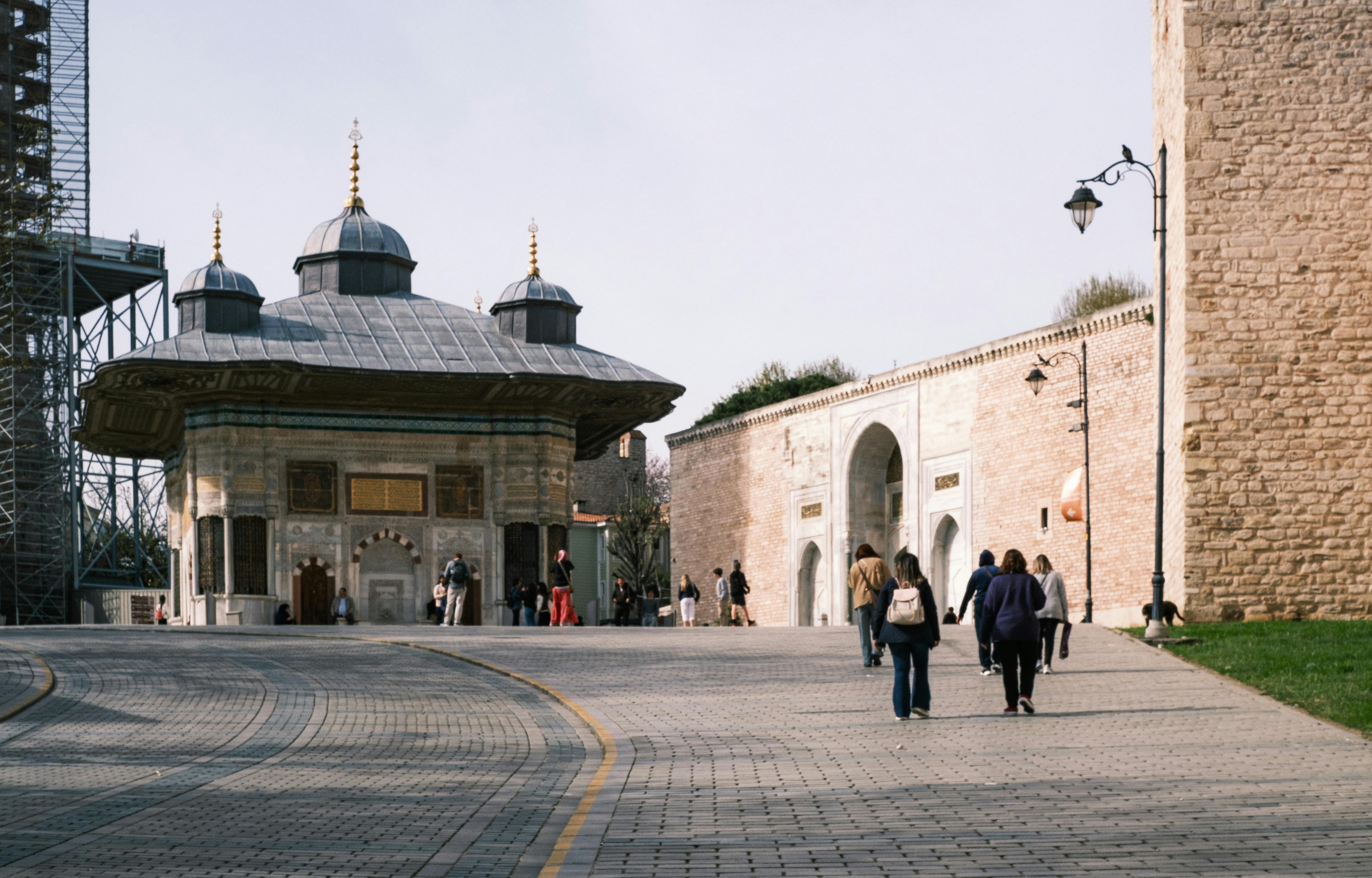 Tourists walking near the Historic Fountain of Sultan Ahmed III in Istanbul, Turkey.