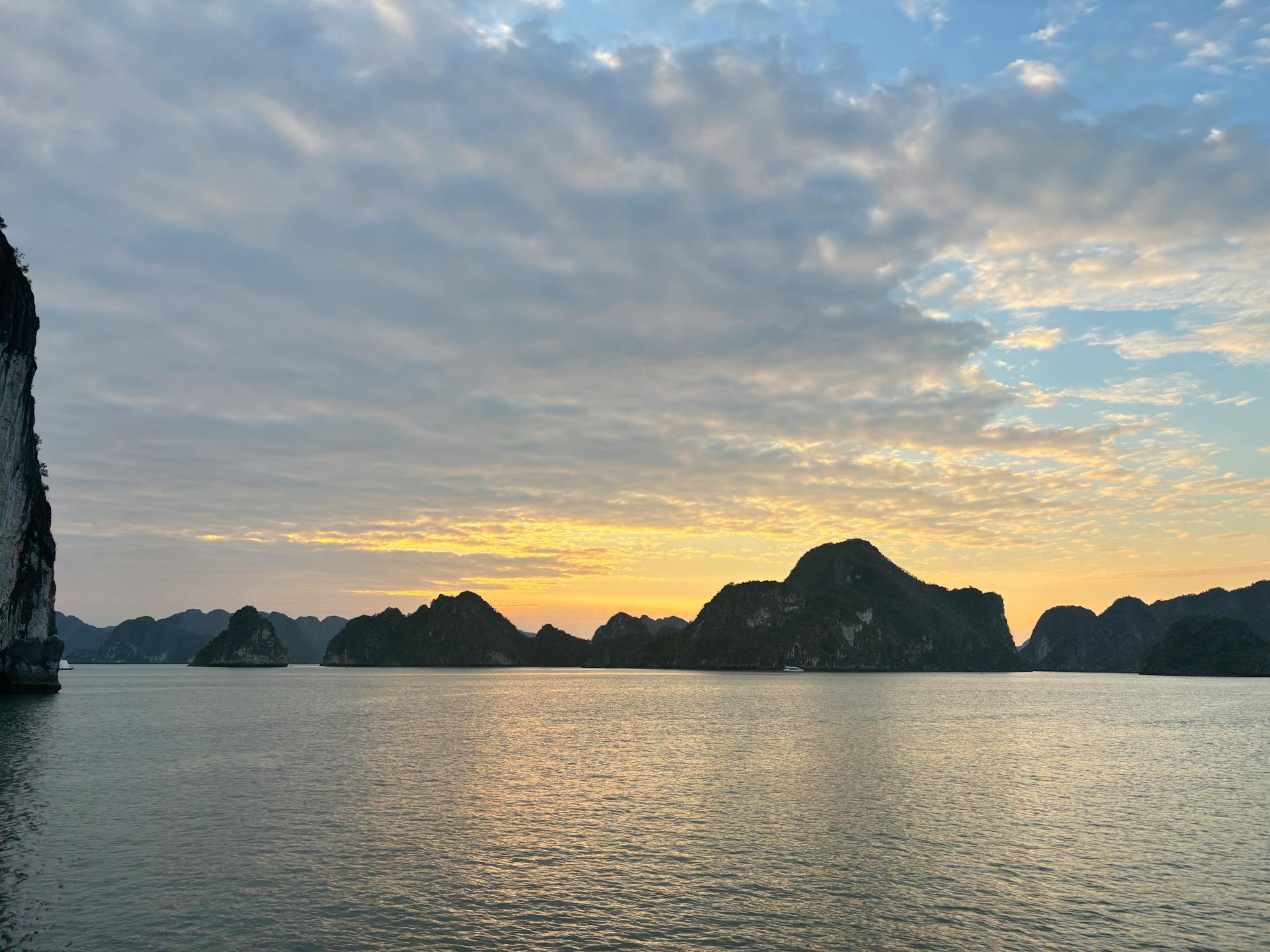 Tranquil sunset view of Halong Bay with scenic limestone islands and calm waters.