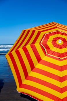Striped umbrella by the ocean in Mar del Plata, capturing a sunny summer day.