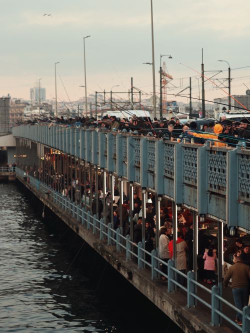 Free A busy scene of fishermen on Galata Bridge in Istanbul with cityscape in the background. Stock Photo
