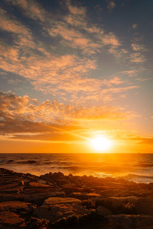 Free Breathtaking sunset over the ocean with vibrant orange and blue hues, capturing serene beauty. Stock Photo