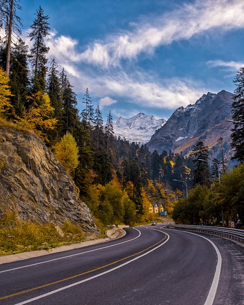 Landscape Photography of Road Between Mountain and Trees