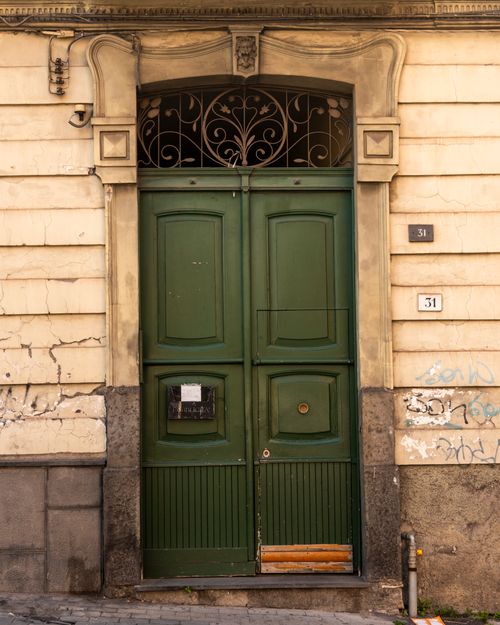 Free Close-up of a vintage green door with ornate arch and weathered walls. Stock Photo