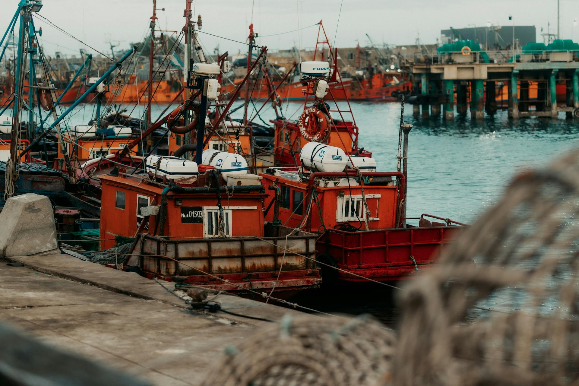 Vibrant red fishing boats lined up at the port, ready for a day at sea. Perfect for travel and maritime themes.