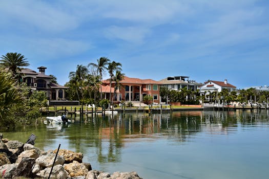 Scenic view of luxury homes along the Sarasota waterfront, surrounded by palm trees and calm waters.