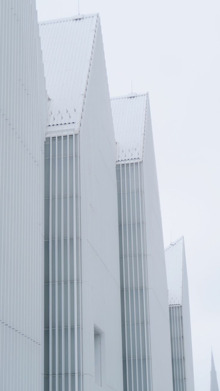 Minimalist geometric architecture showcasing white angular structures under a soft sky.