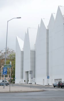 Striking modern white building with peaked roof in city street.