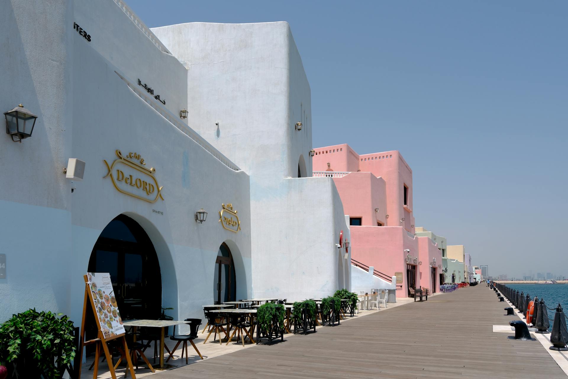 Scenic view of pastel-colored buildings along a waterfront boardwalk.
