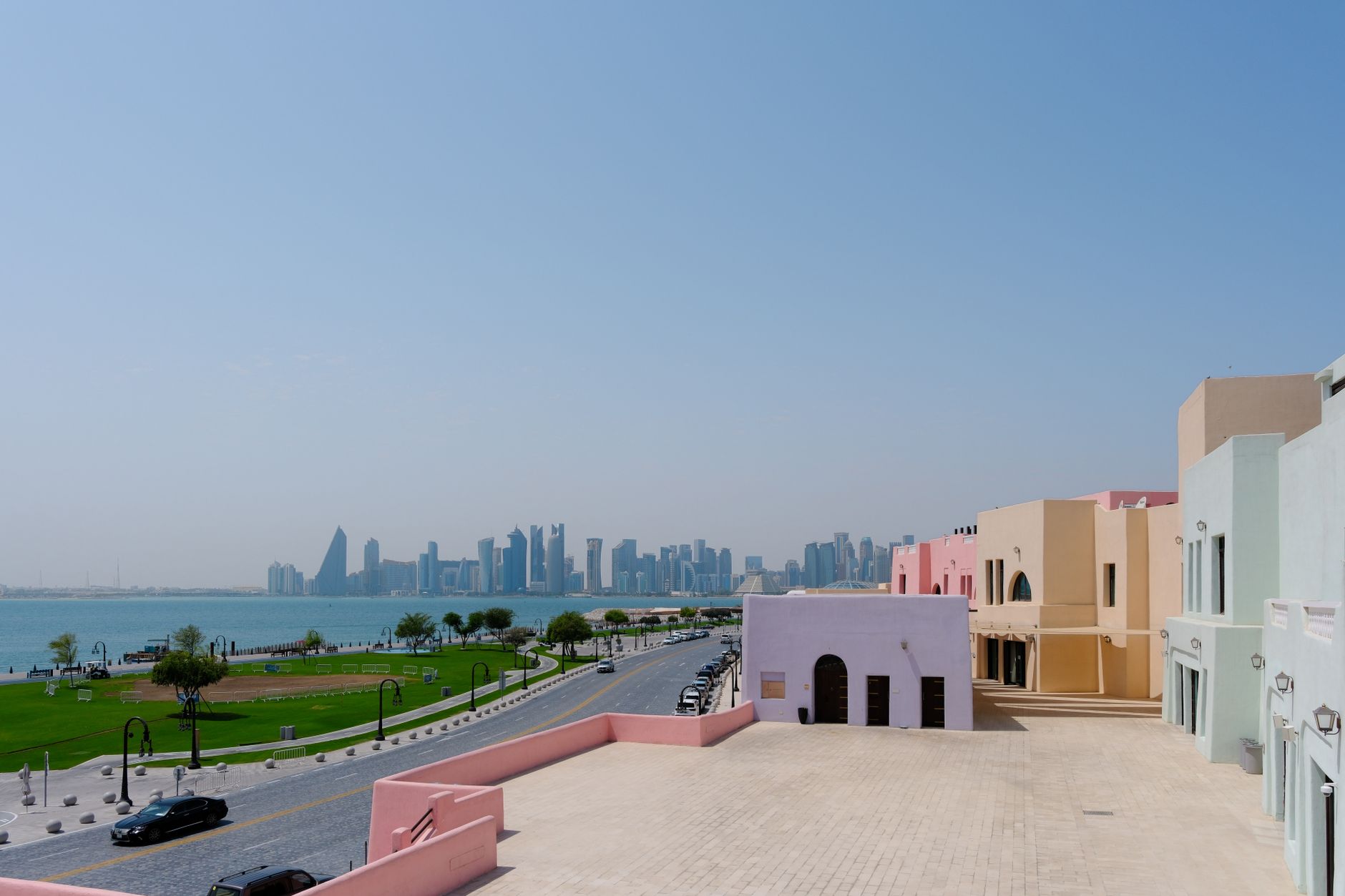 Scenic view of Doha skyline with pastel-colored buildings along the waterfront.