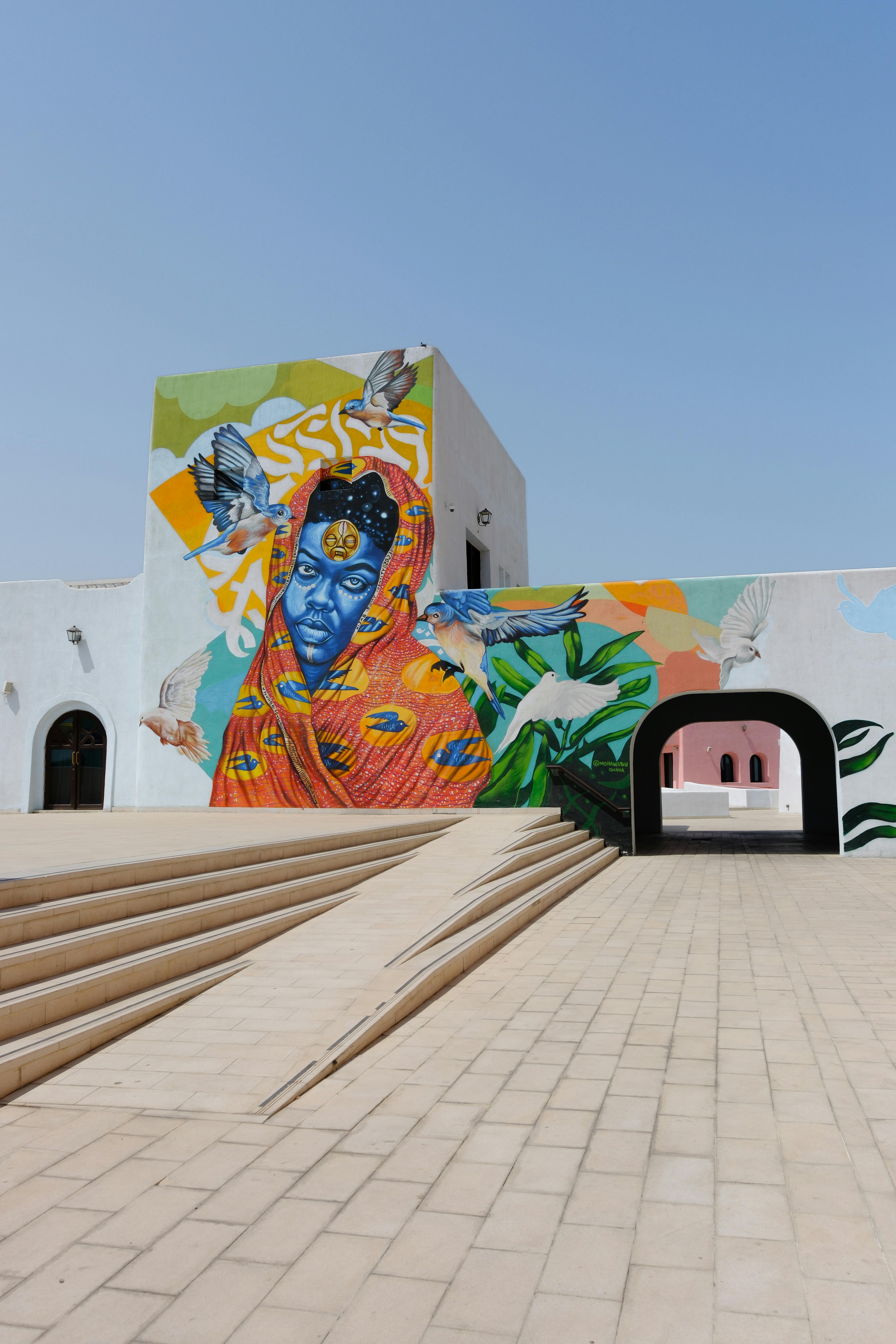 Vivid mural of a woman and birds on a contemporary building exterior.