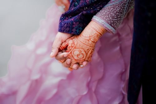Free A close-up of a couple holding hands adorned with intricate henna designs and colorful attire in Pune, India. Stock Photo