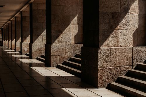 Free Sunlight creates patterns on stone columns and steps in this architectural corridor scene. Stock Photo