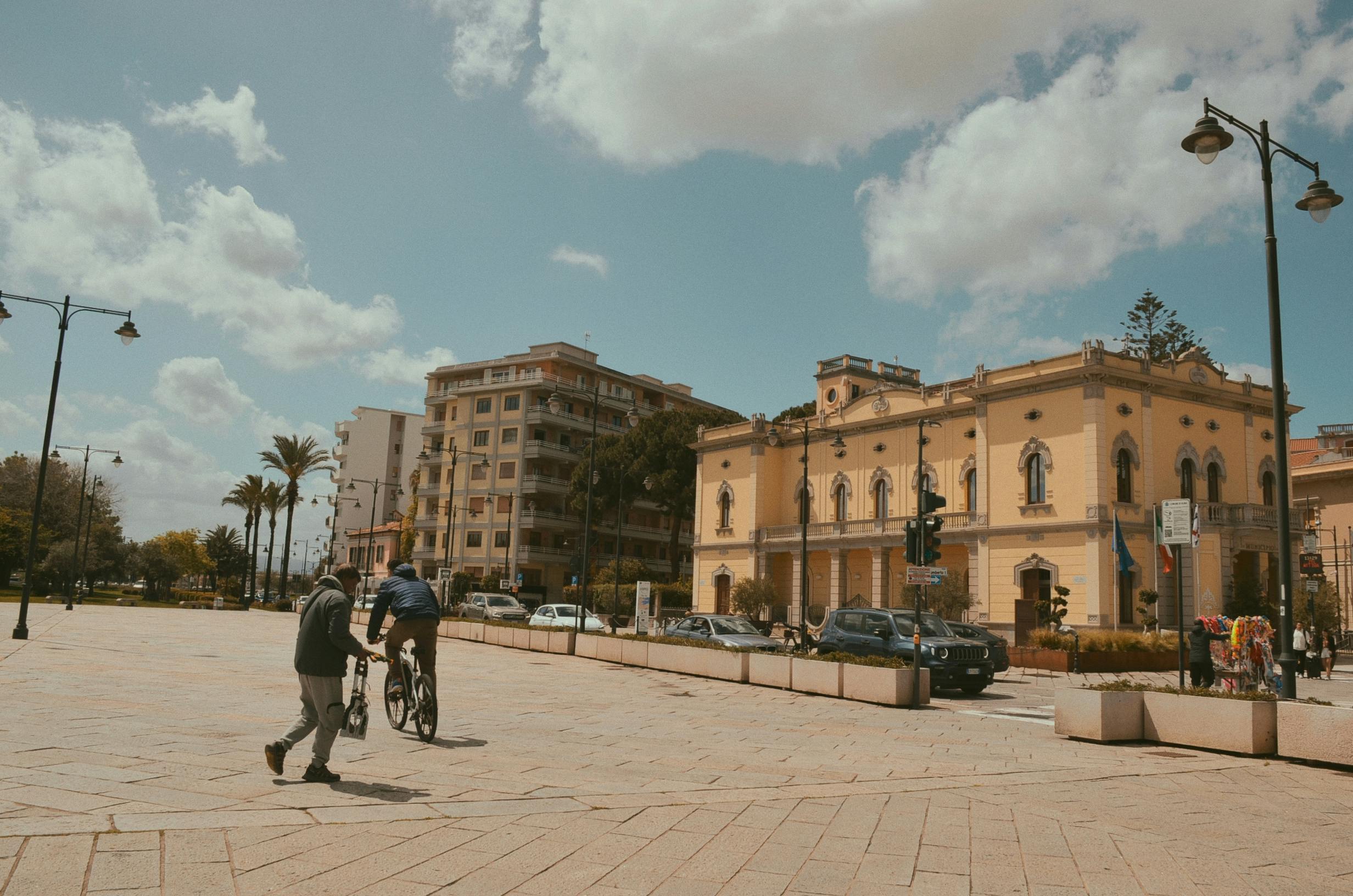 Cyclists enjoying a sunny day in a historic city plaza with charming architecture and vibrant atmosphere.