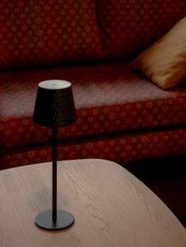 Elegant modern table lamp on a wooden table in a cozy living room setting.